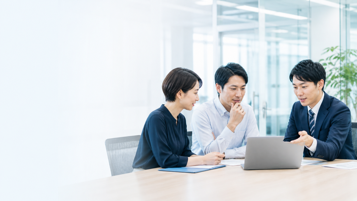 日本人ビジネスパーソンがオフィスでIT相談をしている様子